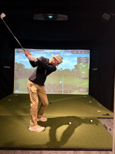 A man swings at a ball while using a golf simulator at Illini Golf, which serves golfers near Bloomington IL