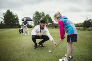 Pro Golfer aids Younger Girl Golfer, golf instruction Pekin IL, golf coaching Pekin IL, golf lessons near Pekin IL, golf swing lessons Pekin IL, private golf lessons Pekin IL, beginner golf lessons Pekin IL, golf training Pekin IL, golf instructor Pekin IL, indoor golf lessons Pekin IL, golf simulator lessons Pekin IL, golf coach near Pekin IL, putting lessons Pekin IL, golf improvement Pekin IL, custom club fitting Pekin IL, golf practice Pekin IL, junior golf lessons Pekin IL, adult golf lessons Pekin IL, golf academy Central Illinois, golf lesson studio Pekin IL, golf swing coach Pekin IL