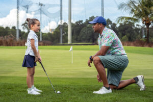 Loving father gives daughter a golf lesson, golf instruction Morton IL, golf coaching Morton IL, golf lessons near Morton IL, golf swing lessons Morton IL, private golf lessons Morton IL, beginner golf lessons Morton IL, golf training Morton IL, golf instructor Morton IL, indoor golf lessons Morton IL, golf simulator lessons Morton IL, golf coach near Morton IL, putting lessons Morton IL, golf improvement Morton IL, custom club fitting Morton IL, golf practice Morton IL, junior golf lessons Morton IL, adult golf lessons Morton IL, golf academy Central Illinois, golf lesson studio Morton IL, golf swing coach Morton IL