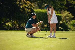 Golf instructor coaching female player discussing shot on the green, golf instruction Pekin IL, golf coaching Pekin IL, golf lessons near Pekin IL, golf swing lessons Pekin IL, private golf lessons Pekin IL, beginner golf lessons Pekin IL, golf training Pekin IL, golf instructor Pekin IL, indoor golf lessons Pekin IL, golf simulator lessons Pekin IL, golf coach near Pekin IL, putting lessons Pekin IL, golf improvement Pekin IL, custom club fitting Pekin IL, golf practice Pekin IL, junior golf lessons Pekin IL, adult golf lessons Pekin IL, golf academy Central Illinois, golf lesson studio Pekin IL, golf swing coach Pekin IL